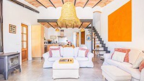 Un salon moderne avec un ensemble canapé, un pouf et un luminaire suspendu.