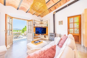 A living room with a TV, sofa, and open door to a balcony.