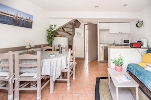 A compact living space with a dining area, kitchenette, and a sofa.