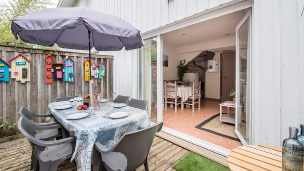 Eine Terrasse im Freien mit einem Esstisch, einem Sonnenschirm und einem Holzdeck.