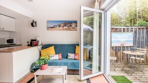 Ein gemütlicher Wohnbereich mit einer Couch, einem Couchtisch und Blick auf einen Strand durch eine Glastür.