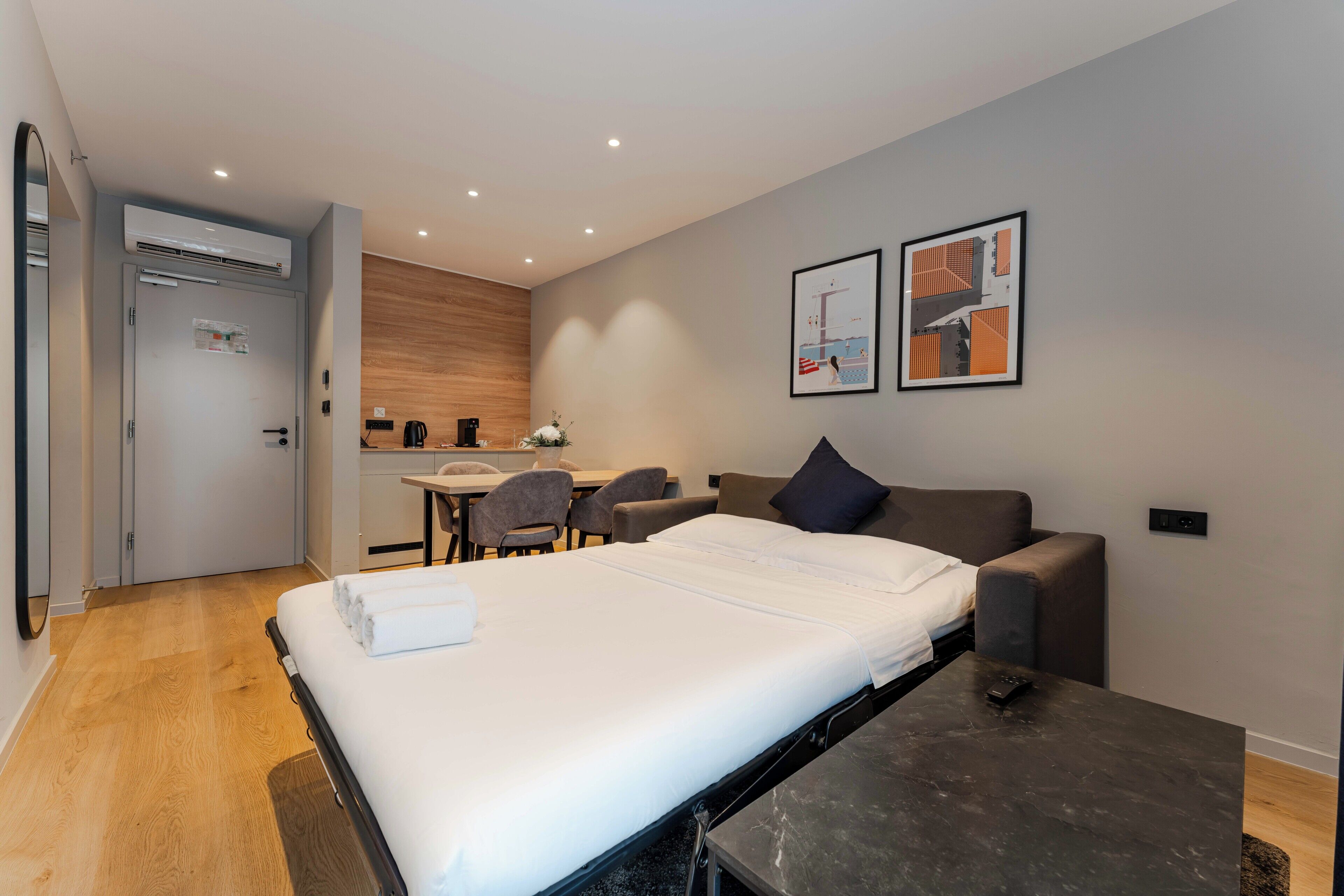 Una habitación de hotel moderna con cama, escritorio, silla, sofá y cafetera.