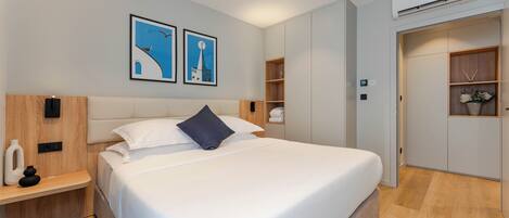 Un dormitorio moderno con una cama grande, una mesita de noche, un armario y dos cuadros en la pared.