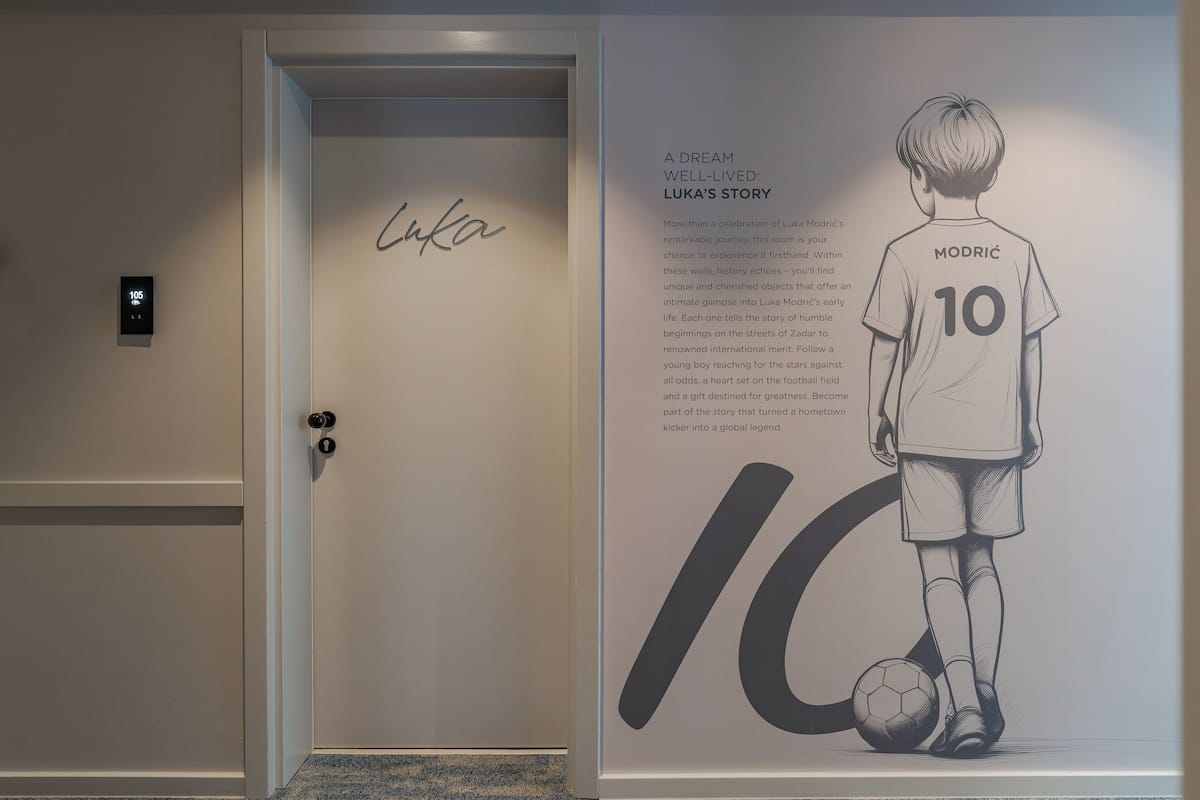 A door with a digital lock and a wall with a large poster of a soccer player named Luka Modrić.