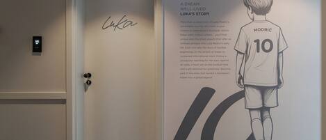 Una puerta con cerradura digital y una pared con un cartel grande de un futbolista llamado Luka Modrić.