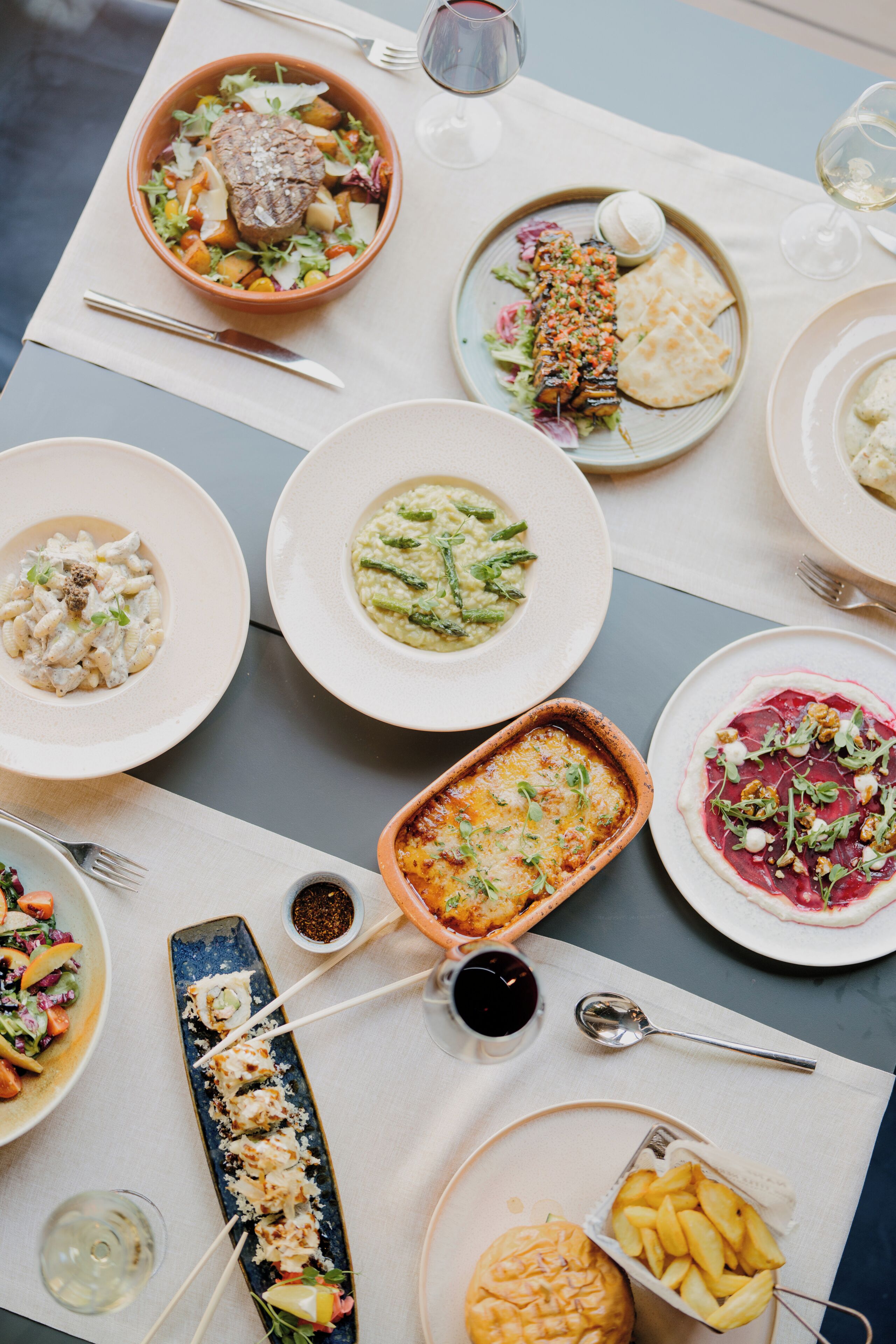 Une table dressée avec différents plats, notamment des pâtes, un plat de viande et un dessert.