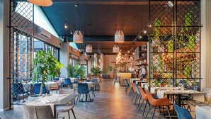 Un restaurante moderno con suelo de madera, sillas azules y lámparas colgantes.