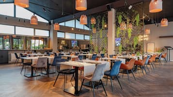 A spacious restaurant with high ceilings, pendant lighting, and a modern interior design.