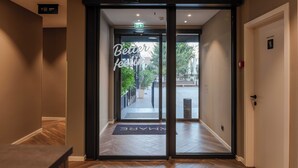Entrada de hotel con puerta de vidrio, un cartel que dice 'Better feeling', un cartel que indica 'Solo personal' y un felpudo con la palabra 'Bienvenido'.