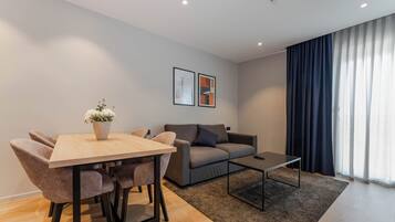 Una sala de estar moderna con una mesa de comedor de madera, un sofá gris y una mesa auxiliar.