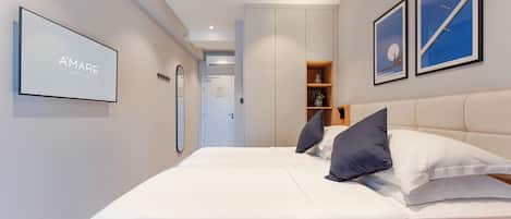 A modern hotel room with a large bed, a wardrobe, and a framed picture on the wall.