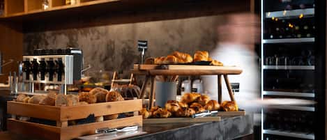 Un comptoir de boulangerie où sont exposés divers produits de boulangerie, avec un réfrigérateur à vin en arrière-plan.