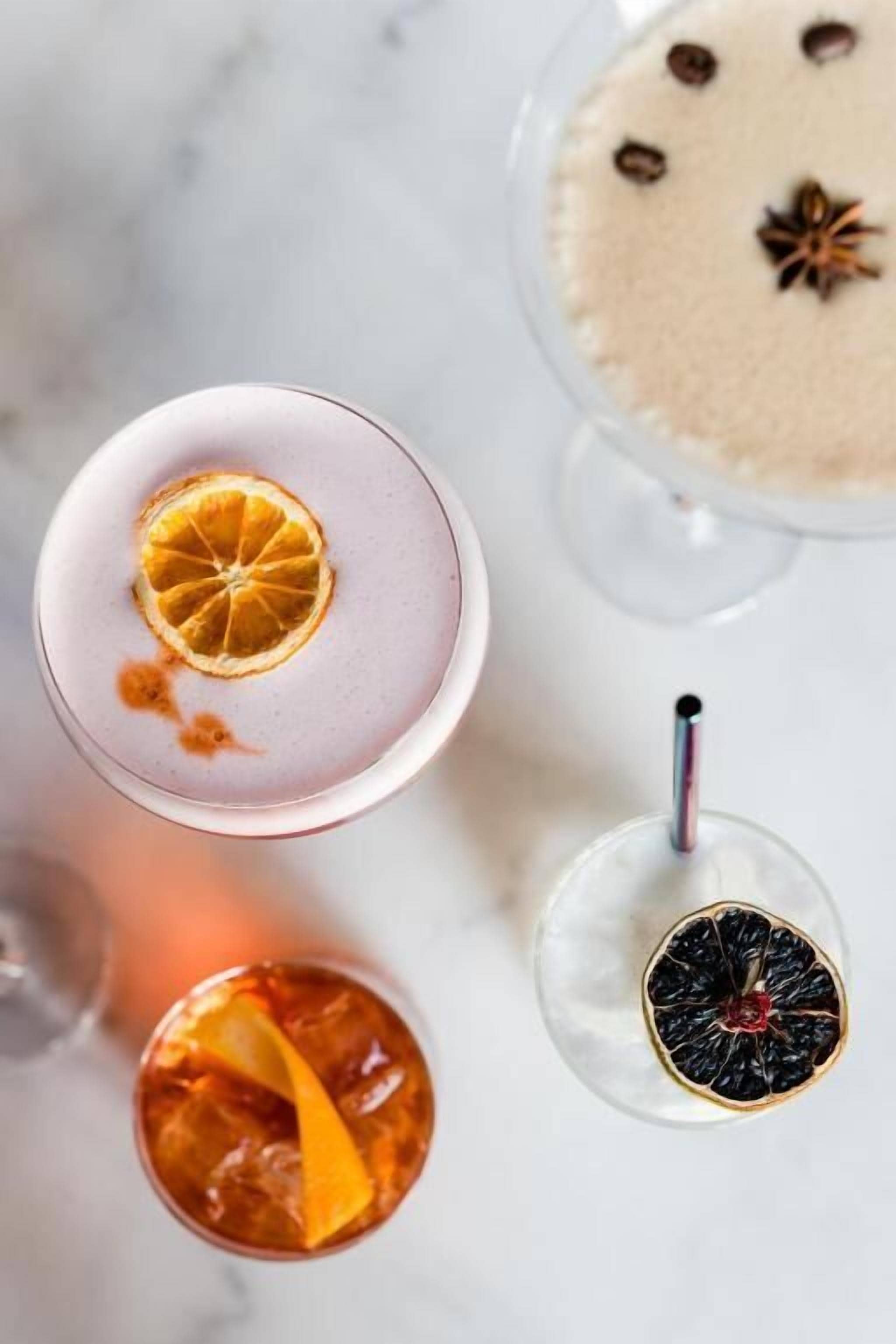 A top-down view of four different drinks, each with unique garnishes.