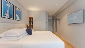 Een moderne hotelkamer met een groot bed, een kledingkast, een spiegel en kunstwerken in lijsten aan de muur.