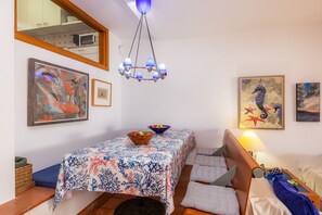Et værelse med spisebord, seng, sofa, lysekrone og billedkunst på væggene.