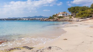 A beach with clear water, a sandy shore, and a house with a view of the sea. - Holiday Home Es Niu with Sea View, Garden and Wi-Fi (Portocolom)