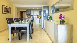 A modern kitchen with a dining area, a refrigerator, and a counter with a mirror. - Holiday Apartment 'Daniela' next to the Beach with Sea View, A/C, Balcony & Wi-Fi (Pollenca)