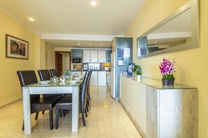 A modern kitchen with a dining area, a refrigerator, and a counter with a mirror.