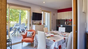 An open-plan living area with a dining table set, a sofa, and a TV.