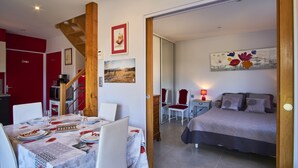 A bedroom with a bed, a bedside table with a lamp, a chair, and a painting on the wall.