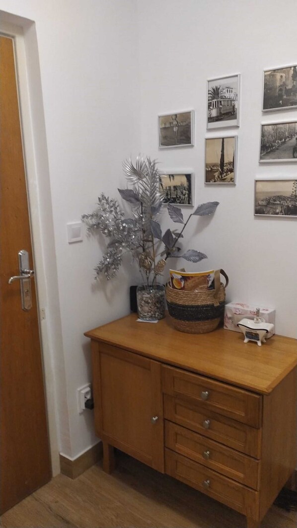 A wooden cabinet with drawers, a potted plant, and a basket with a bag. - Apartment Lea (Dubrovnik)