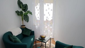 Una sala de estar con un sofá color turquesa, un sillón a juego, una mesa de centro y una planta grande.