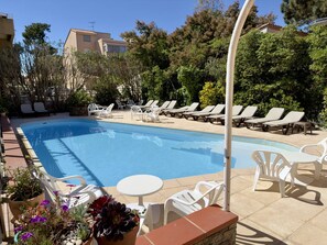 Una piscina con lettini e piante in vaso.