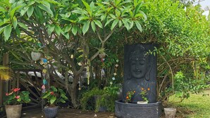 En trädgård med en Buddha-staty, krukväxter och en träaltan.