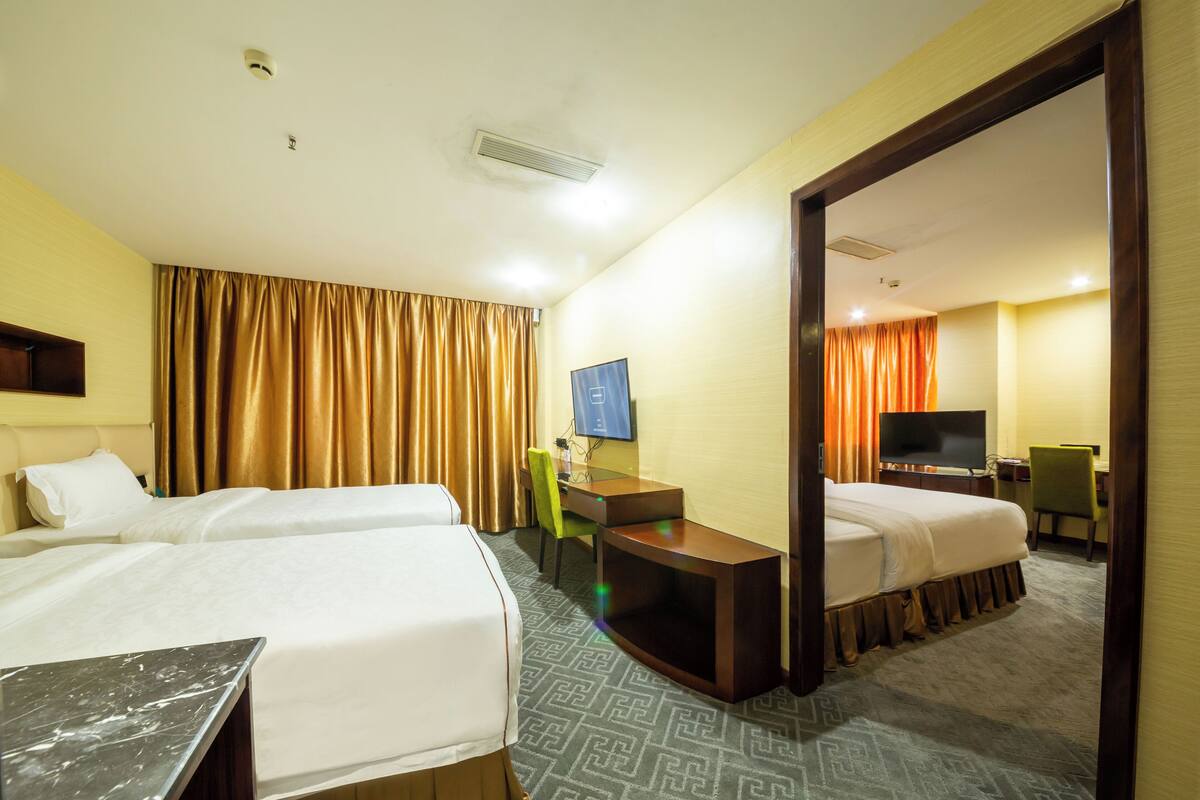 A hotel room with two beds, a desk, a chair, a television, and a mirror.