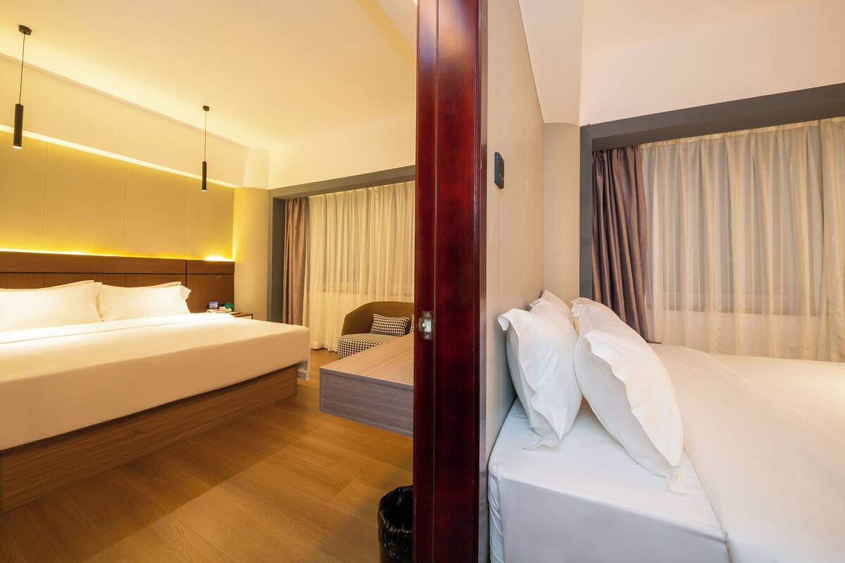 A hotel room with a large bed, a smaller bed, a desk, and a wardrobe.