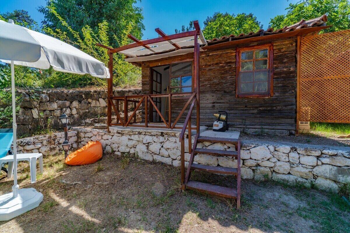 A rustic cabin with a stone foundation, a wooden porch, and a small window.