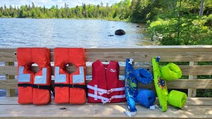 A wooden bench with life jackets and a green flotation device on it.