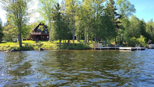 A lakeside cabin with a dock and a small pier, surrounded by lush greenery and trees. - Alpenglow - 3 bedroom, 2 bath home on Haley Pond (Rangeley)
