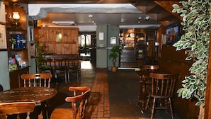 Een gezellig restaurant met houten meubels en een vloer van baksteen.