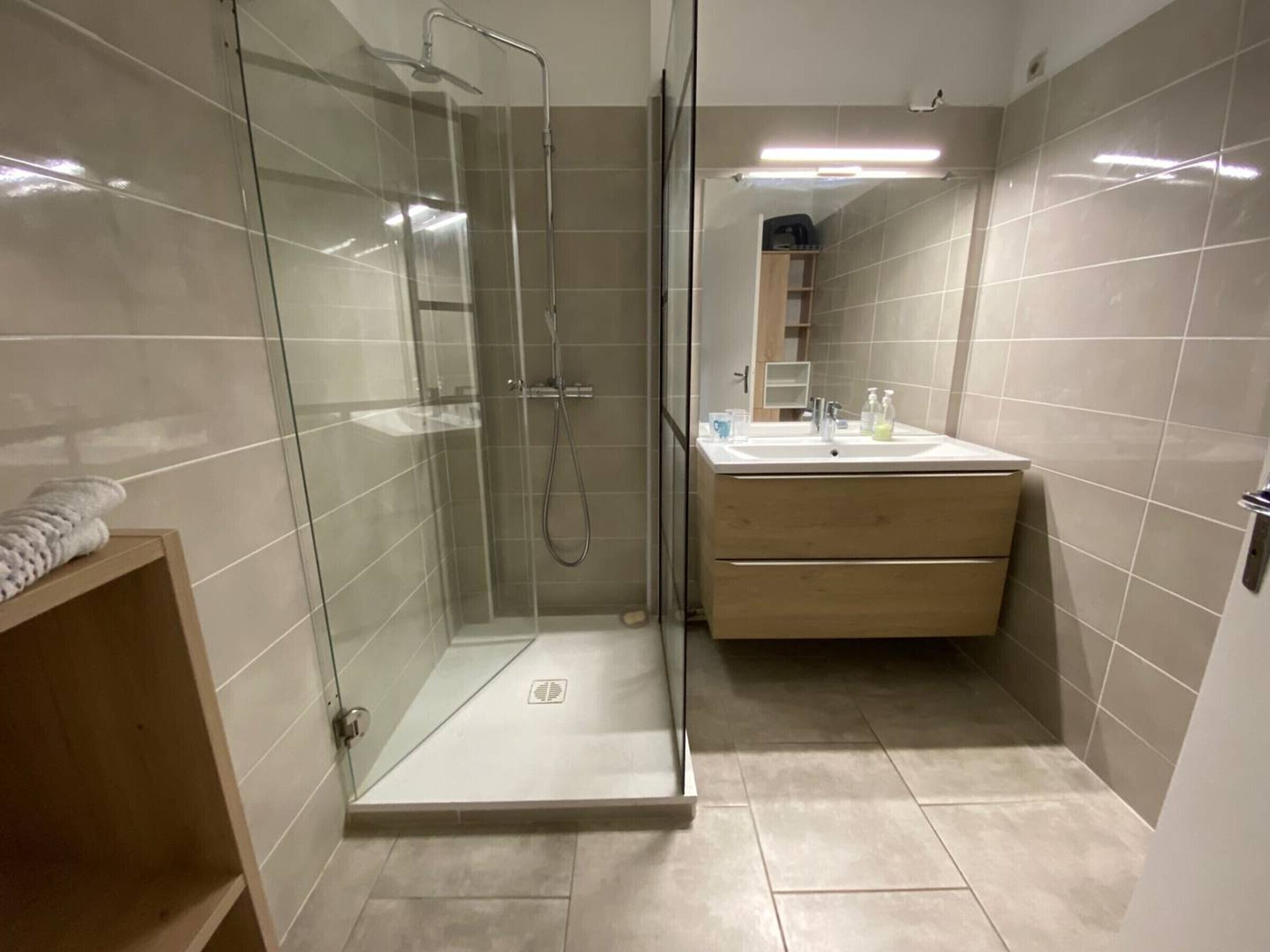 Une salle de bain moderne avec une douche à parois de verre, un lavabo et un meuble-vasque en bois.