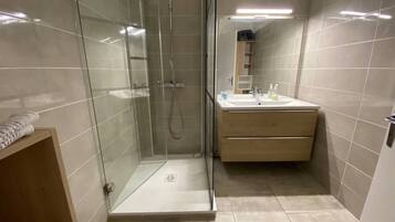Une salle de bain moderne avec une douche à parois de verre, un lavabo et un meuble-vasque en bois.