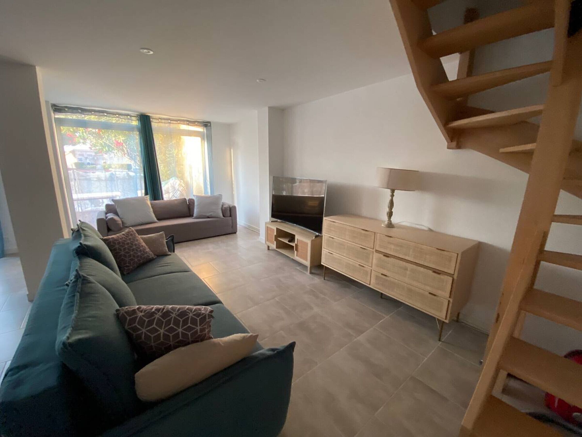 En moderne stue med sofa, fjernsyn og træskab.