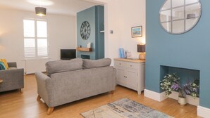 Una sala de estar con un sofá gris, televisor, reloj, chimenea y una pared de acento azul.