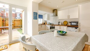 Una cocina moderna con armarios blancos, un microondas y un comedor con mesa y sillas.