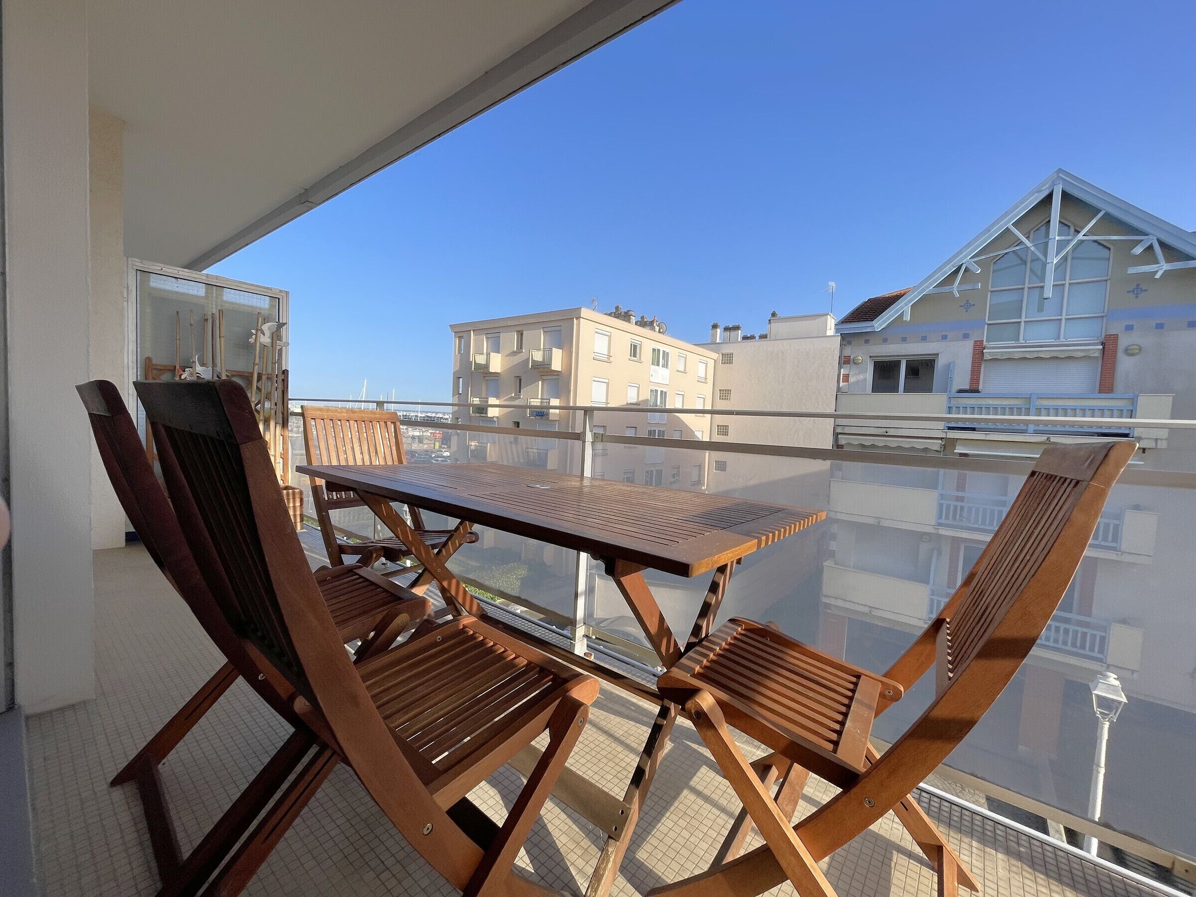 Ein Balkon mit Holztisch und -stühlen, der einen Blick auf die Stadt bietet.