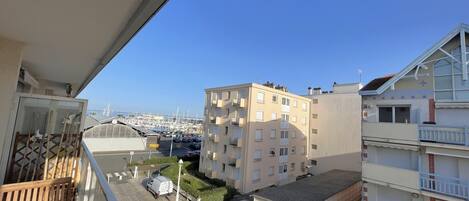 A balcony overlooking a marina with boats, adjacent buildings, and a clear blue sky.
