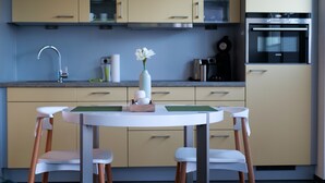 Una cucina moderna con un tavolo rotondo, due sedie, un vaso con fiori e un forno Siemens.