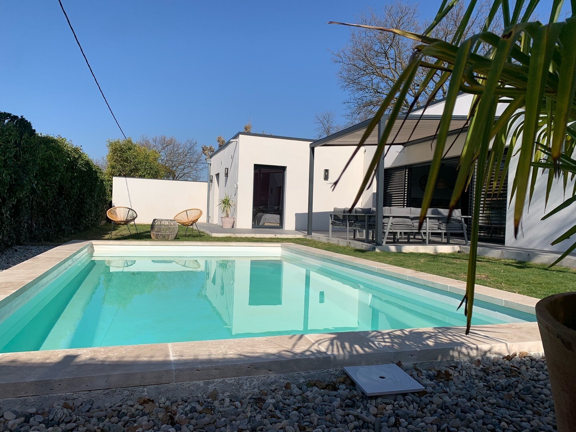 Een modern huis met een zwembad, tuinmeubilair en een patio.