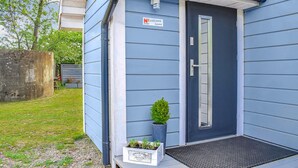 Ein Haus mit dunkelblauer Fassade, einer weißen Tür mit silberner Klinke und einem Willkommensschild.