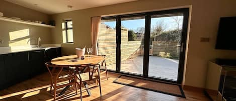 A spacious kitchen with a dining area, large sliding glass doors leading to a backyard, and a flat-screen TV.