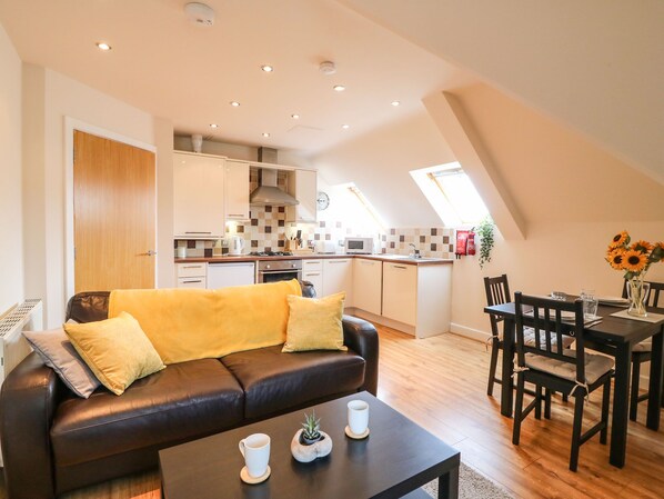 A modern apartment with a living room, kitchenette, and dining area.