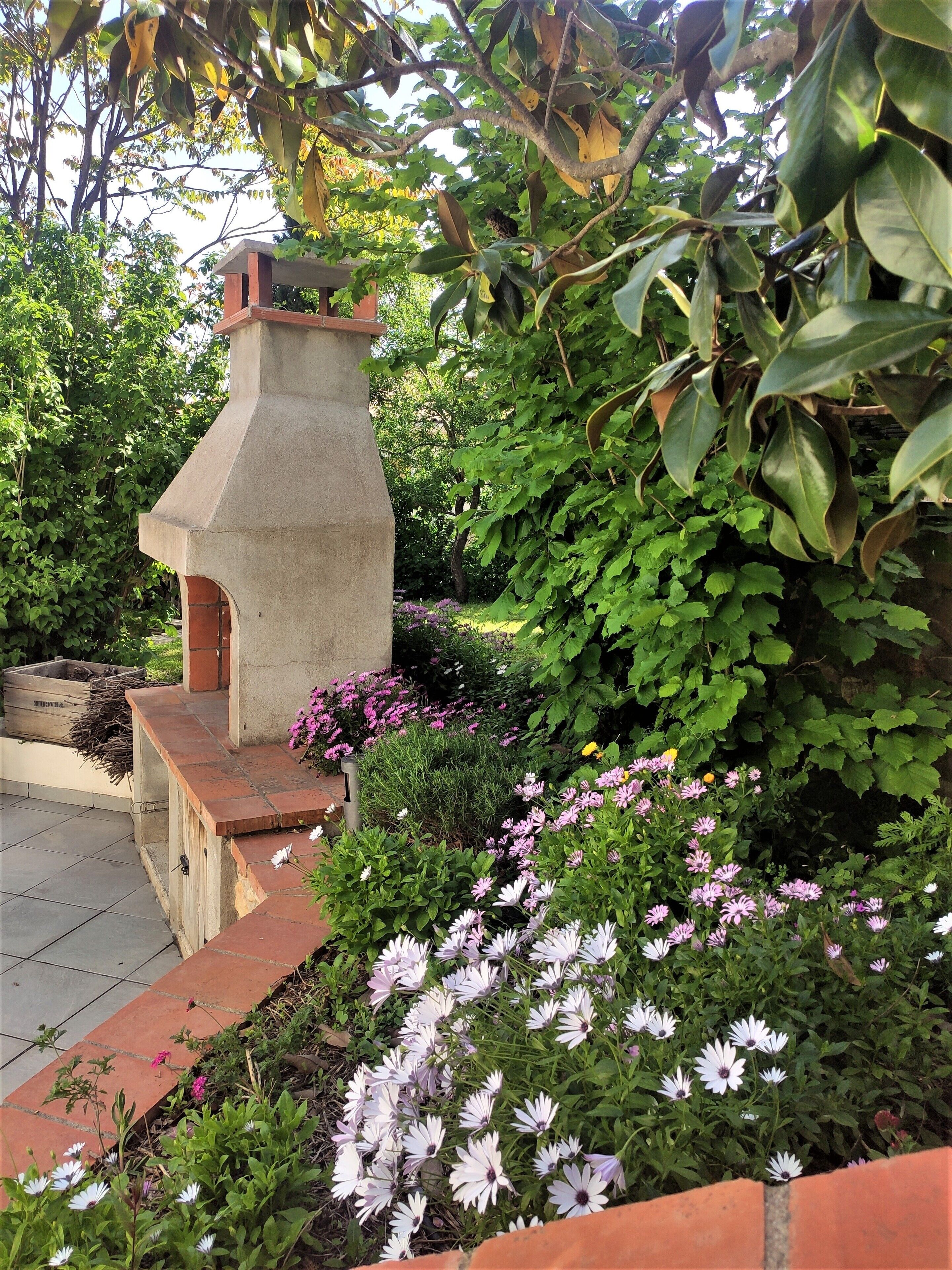 A garden with a stone structure, possibly a fountain or decorative feature, surrounded by various plants and flowers.
