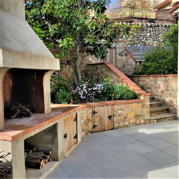 An outdoor kitchen area with a stone wall, wooden steps, and a fire pit.