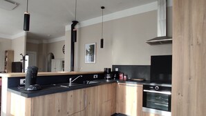 A modern kitchen with wooden cabinets, a black countertop, and stainless steel appliances. - "La Casa De La Font" classified *** near Céret and Thuir  private parking (LLAURO)