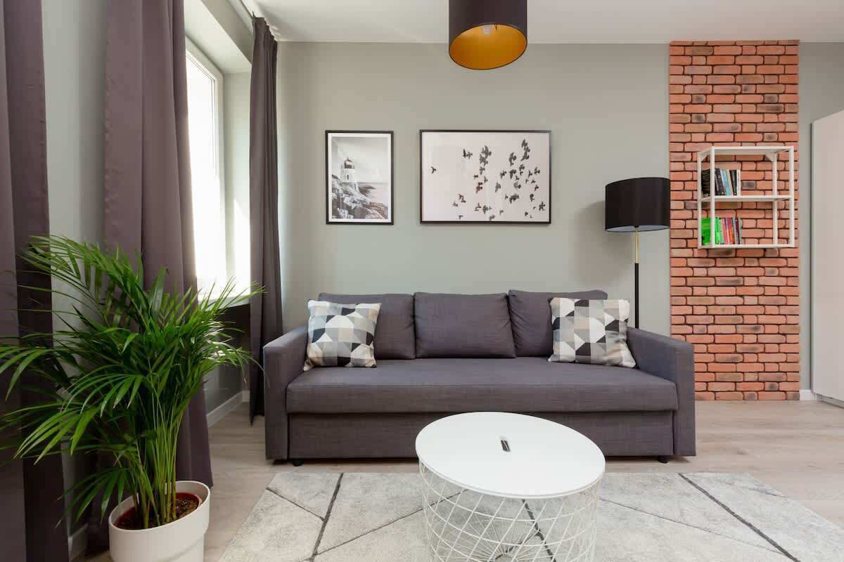 Una sala de estar moderna con un sofá gris, una mesa de centro blanca y una planta en maceta.